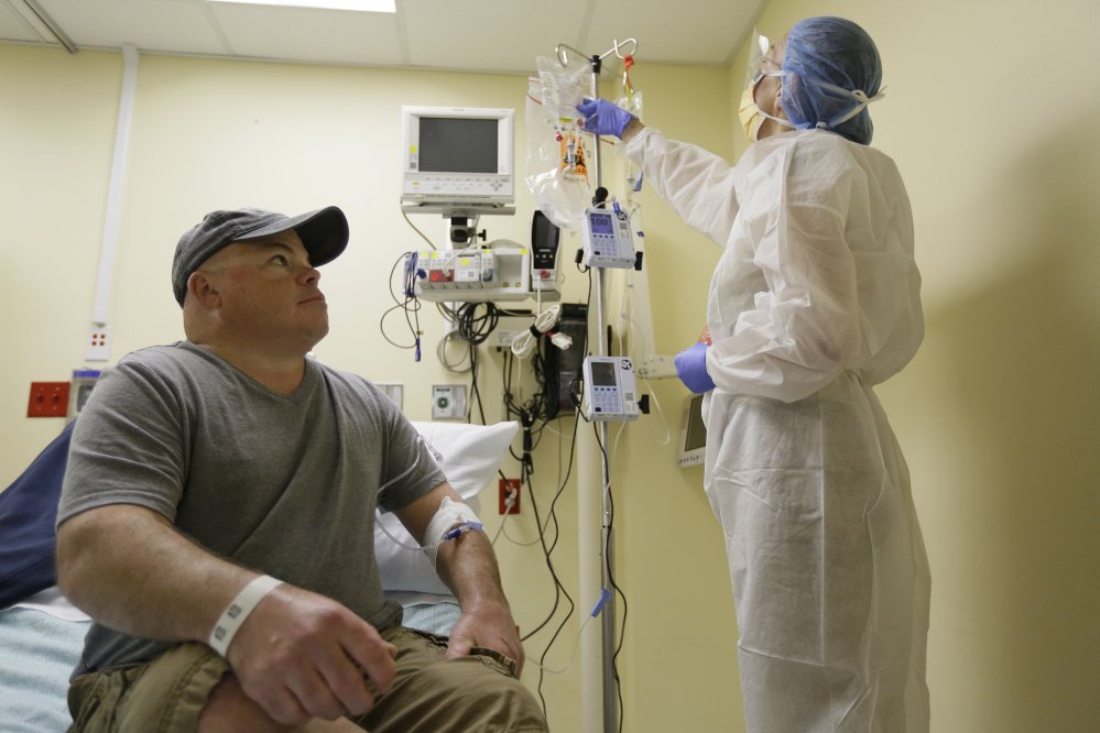 Brian Madeux, 44, looks up at nurse practitioner Jacqueline Madde on Monday while receiving the first human gene editing therapy at the UCSF Benioff Children's Hospital in Oakland, Calif.  Madeux, who has a metabolic disease called Hunter syndrome, will receive billions of copies of a corrective gene and a genetic tool, through an IV,  to cut his DNA in a precise spot.