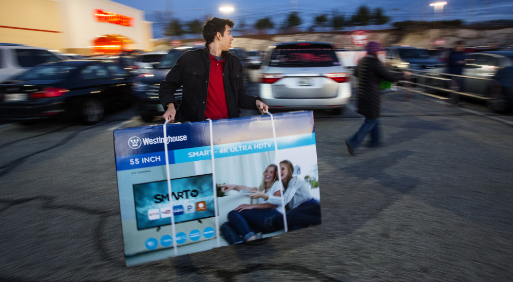Clockwise from top, Yousef, 5, waits for his mother to finish shopping at Best Buy in the Maine Mall just after midnight on Black Friday; Carol Rickett of Portland uses hand warmers while waiting in line for Target to open at 6 a.m.; Bregan Deleon, a Target employee, carries a 55-inch television to a customer's car.
