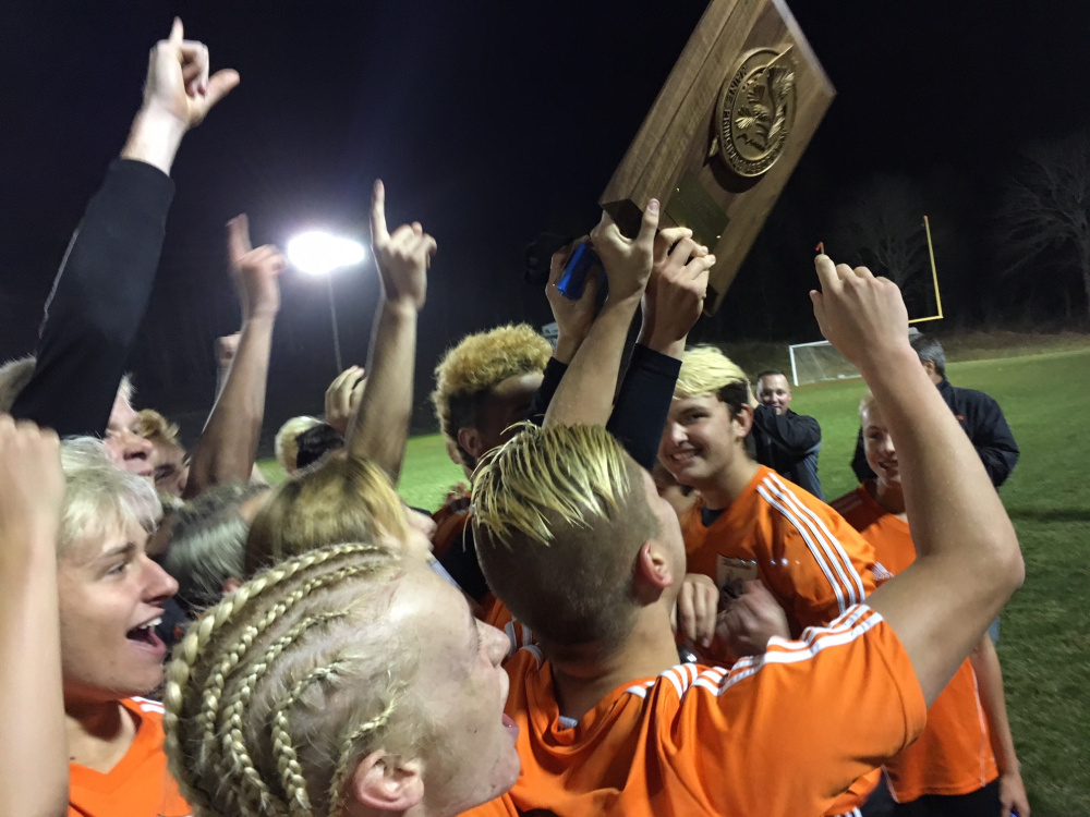 The Winslow boys soccer team holds up the Class B North championship plaque after defeating Washington on Thursday in East Machias.