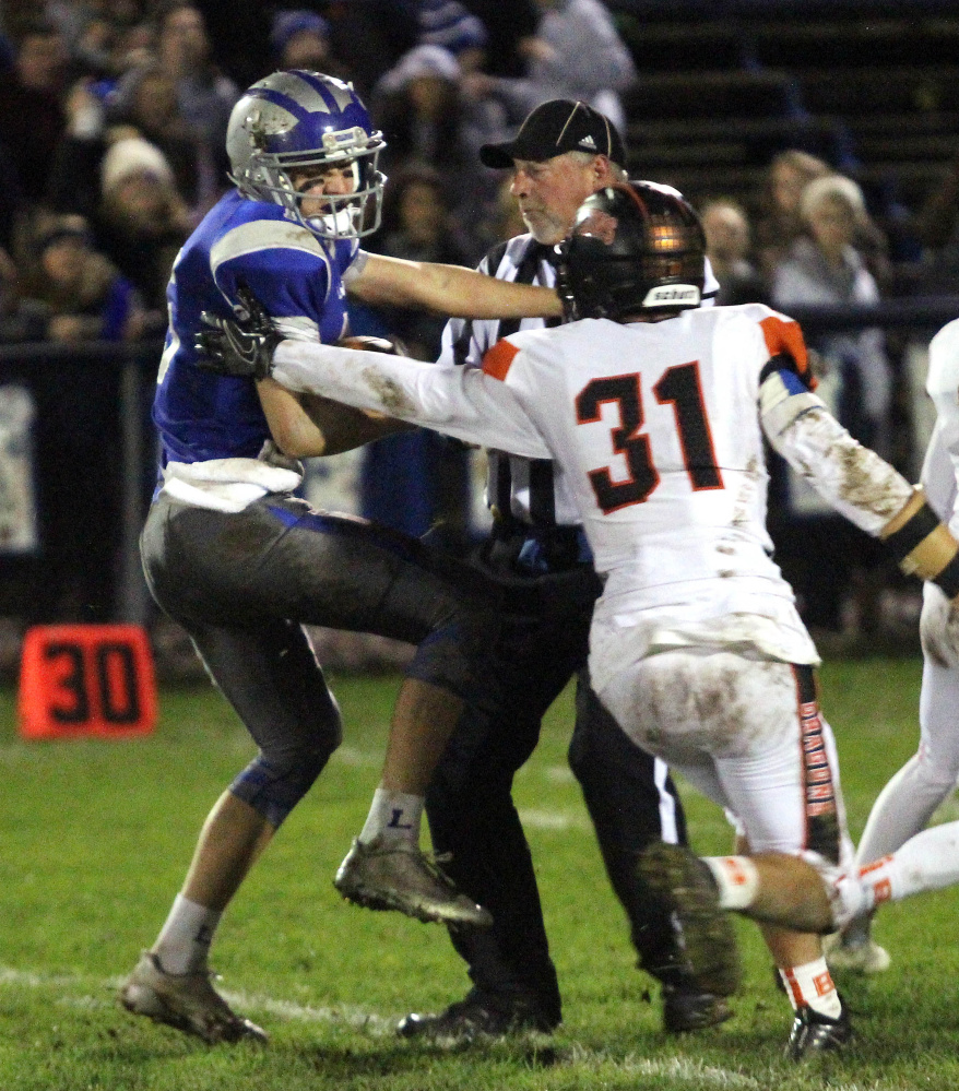 Lawrence's Jared Dodge runs into an official after catching a pass from quarterback Braden Ballard during first-half of a Pine Tree Conference Class B semifinal game against Brunswick on Friday night in Fairfield. Making the eventual tackle for Brunswick is Sam Dorval.