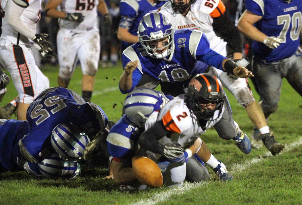 Lawrence's Braden Ballard, top, tries to fall on a fumble by Brunswick's Dalton Dickey during first-half of a Pine Tree Conference Class B semifinal game Friday night in Fairfield.
