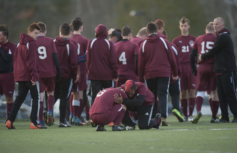 Richmond's Ben Gardner, bottom left, is comforted by teammate Jordan Perry after the Bobcats fell to Bangor Christian in the Class D state championship game Saturday at Hampden Academy.