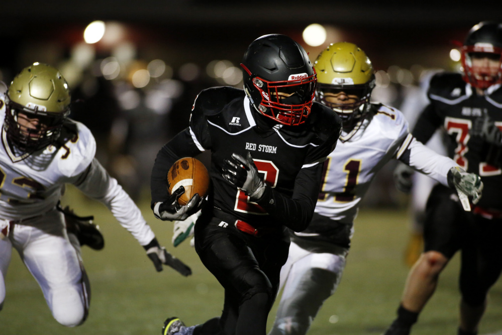 Scarborough's Jarett Flaker carries the ball as Thornton Academy's Thomas Palmer, left, and C.J. LaBreck try to tackle him Friday night during the Class A South championship game at Scarborough High.