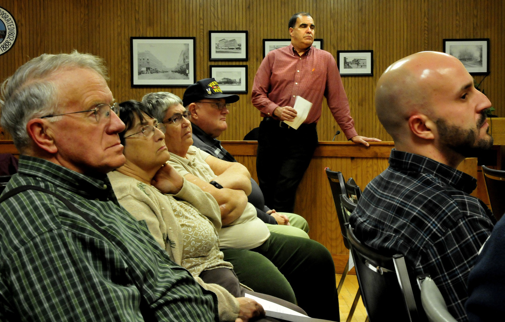 Ernie Martin, background, project manager for the Maine DOT, listens to speakers Monday during a meeting regarding the Trafton Road project at City Council in Waterville.