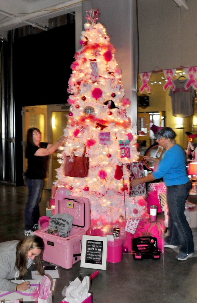 A Christmas tree sponsored by Doug's Garage is decorated Tuesday for the upcoming Sukeforth Family Festival of Trees at the Hathaway Creative Center in Waterville. Decorating the tree from left are Cindy Witham and Sue Blaisdell. On the floor wrapping gifts is Andrea Manzo.