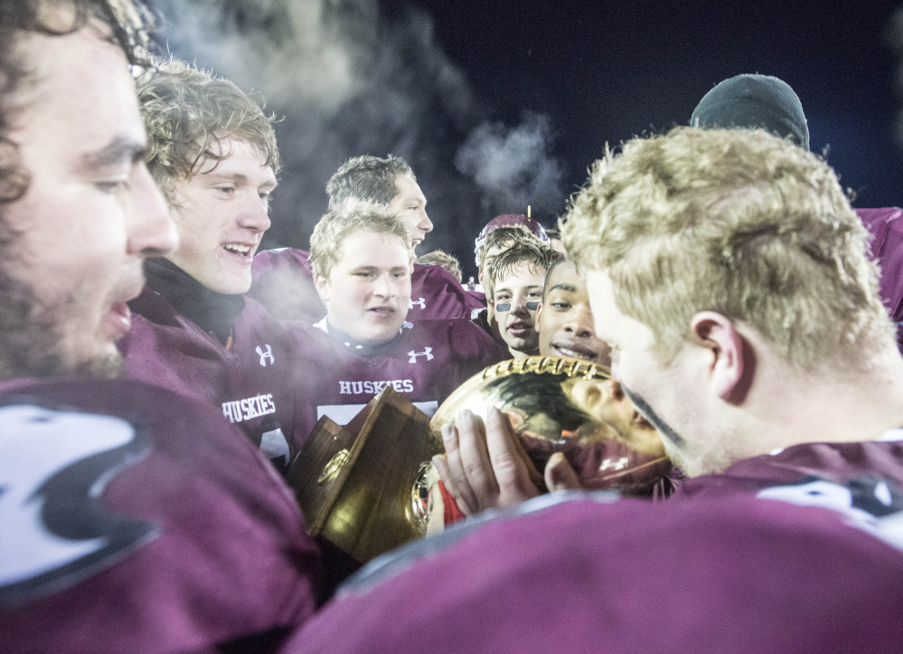 Maine Central Institute players celebrate with the Gold Ball after they defeated Cape Elizabeth in the Class C state game Friday night in Orono.