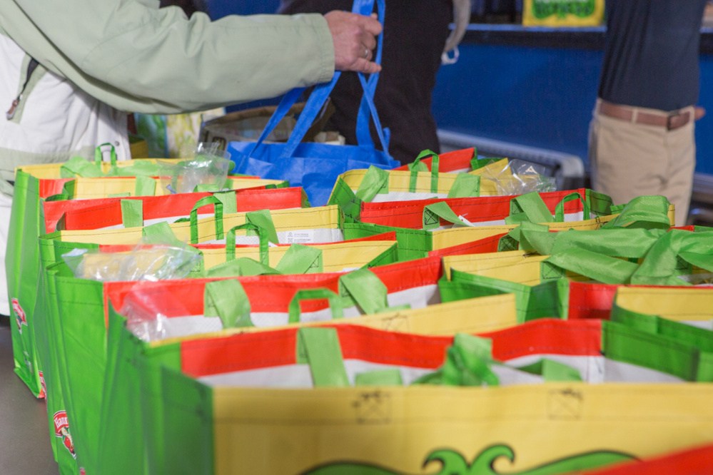 Volunteers and eighth-grade students help area residents in need Monday at St. Michael School in Augusta, where students stuffed and distributed over 200 bags of Thanksgiving food.
