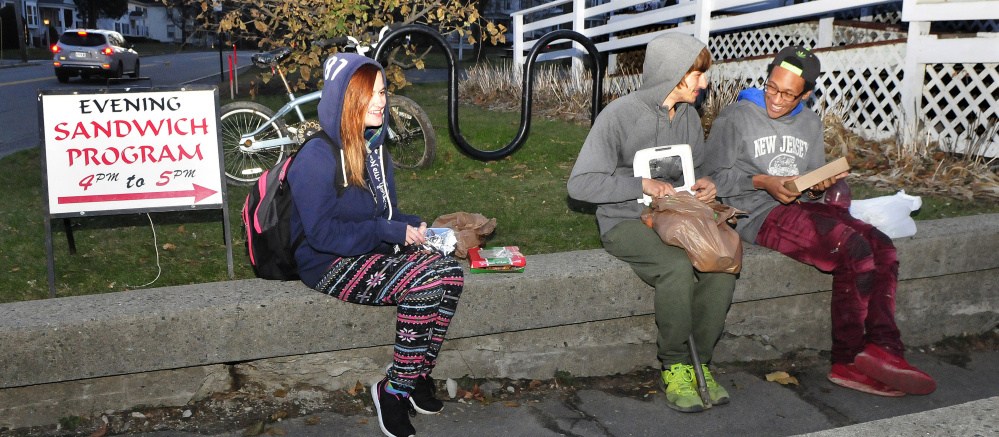 Three young recipients of the Universalist Unitarian Church Evening Sandwich program eat a meal outside the church in Waterville on Tuesday. From left are Montana Gulasky, Gradyn Dyer and Maliek Kirby-Milkins.