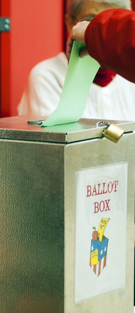 A voter drops a ballot into the ballot box Tuesday at the Winthrop Town Office, where polls are open until 8 p.m.