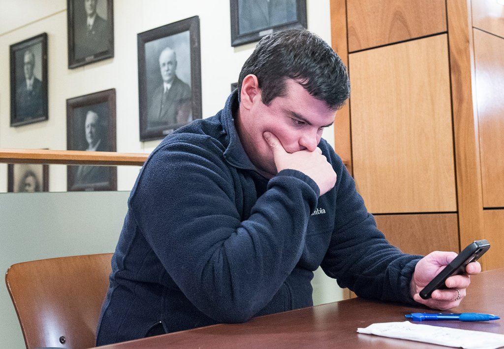 Auburn mayoral candidate Adam Lee checks his email as he keeps a running tally on a napkin on the second floor of Auburn Hall on Tuesday night as election results start to come in.
