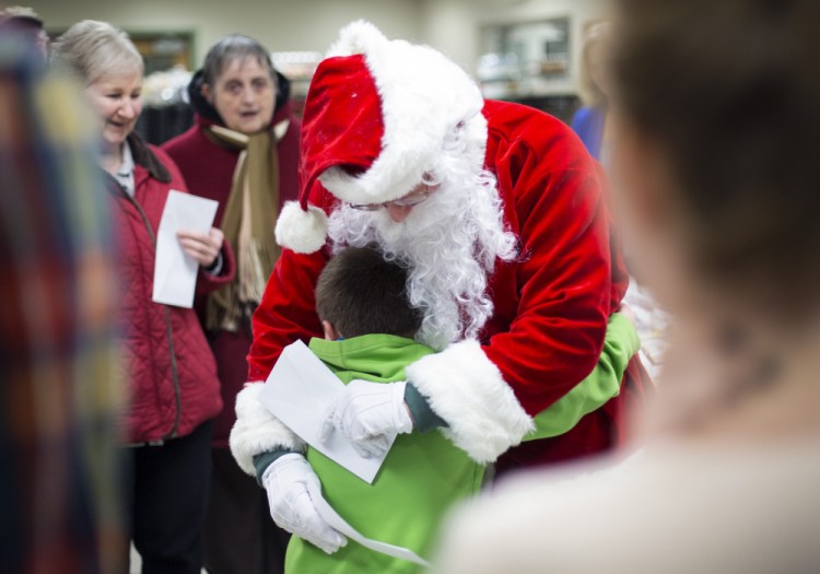 The Secret Santa gets a hug from Shawn Michaud, 5, of Standish after giving Shawn's mom an envelop with a $100 bill in it.