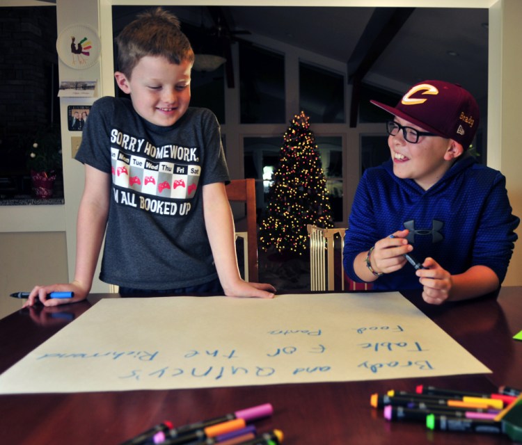 Quincy Emmons, left, and Brady Alexander work on a poster Thursday in Richmond. They plan to staff a table Friday evening at the Richmond tree-lighting to collect nonperishables for the Richmond Food Bank.