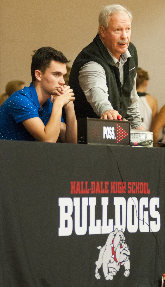 Athletic director Colin Roy, top, talks to scoreboard operator Logan Dupont about how to operate the alternating possession arrow sign at the scorers table on stage in the Penny Gym on Tuesday at Hall-Dale High School in Farmingdale. Roy was explaining that he should wait until the after an inbounds pass is actually caught before hitting the switch and flipping the arrow.