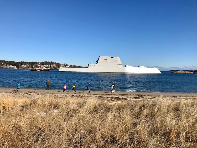 Children run on the beach near Fort Popham as BIW’s new Zumwalt destroyer cruises past on its way into Sagadahoc Bay on Monday afternoon. 

