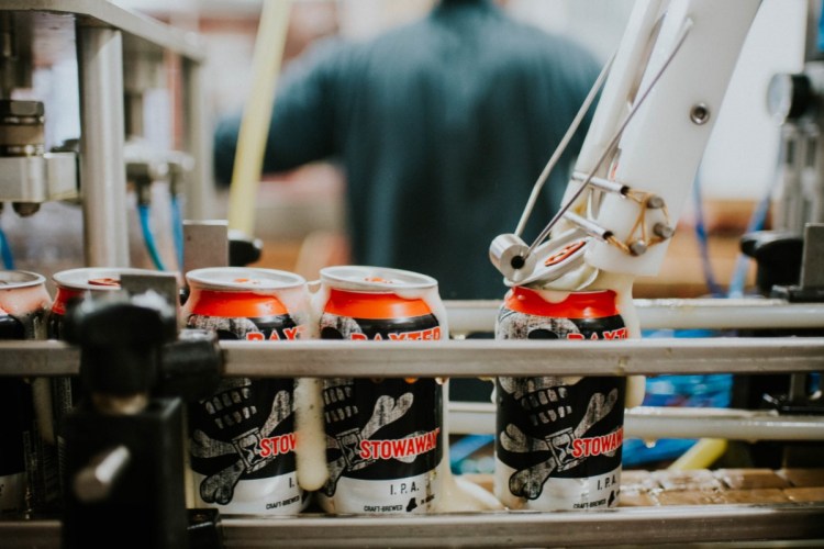 Cans of Baxter's Stowaway IPA are topped off at their Lewiston brewery. Baxter opened 7 years ago in Lewiston's Bates Mill and brewed more than 15,000 barrels of craft beer last year.