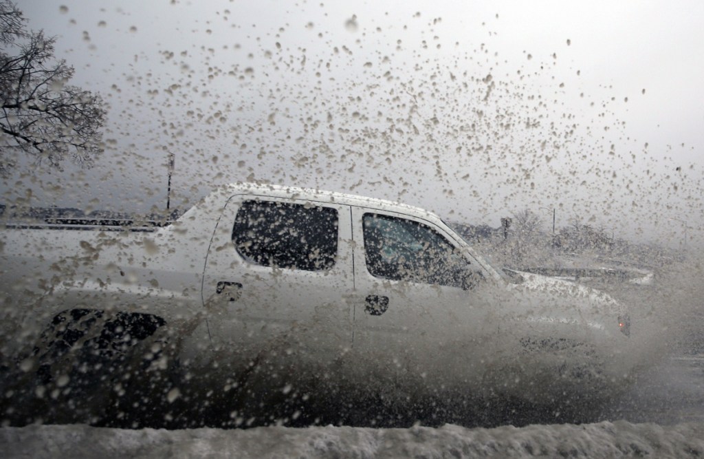 A pickup truck slices through a deep puddle Tuesday afternoon on Baxter Boulevard. The wintry mix of precipitation caused minor flooding on Portland roads.