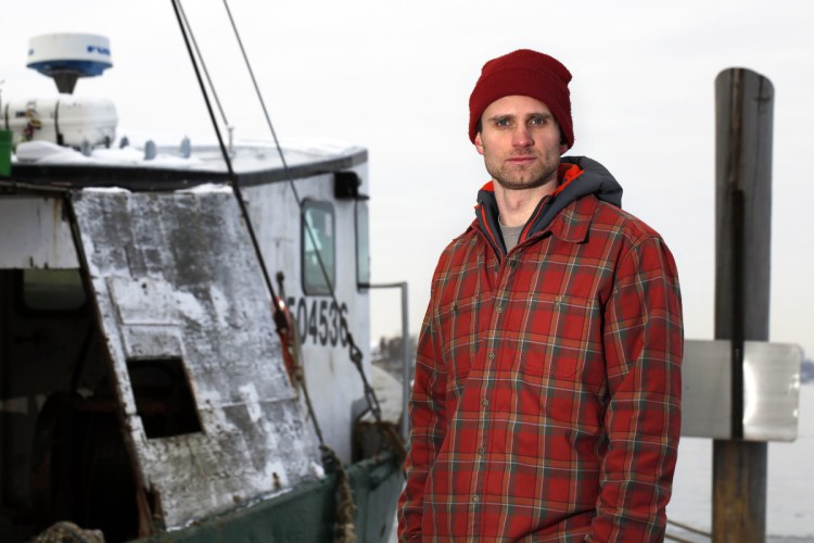 Cooper Van Vranken next to the scallop dragger E Cosi II on the Peaks Island waterfront near his home.