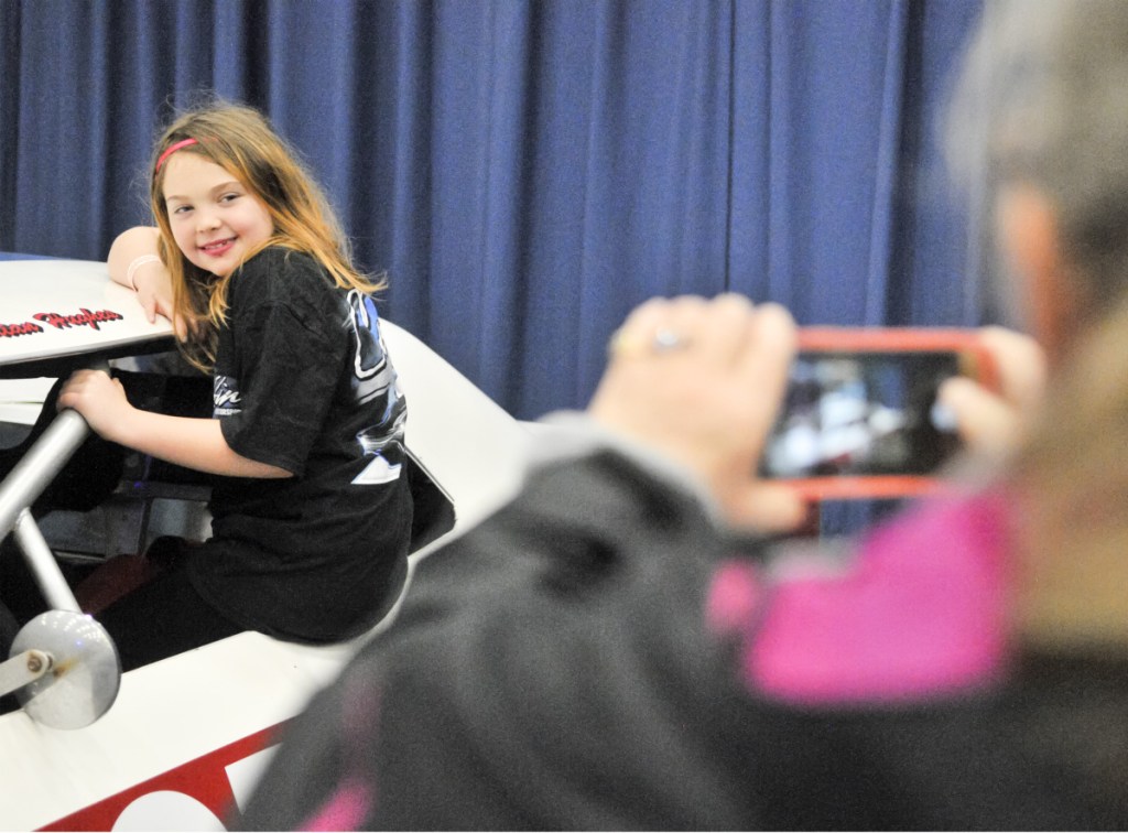 Patricia Williams of Richmond, left, poses in a replica of a 1967 Chevelle as her grandmother Connie Peacock of Dresden snaps a photo in the Wicked Good Vintage Racing Association booth Saturday at the Augusta Civic Center.