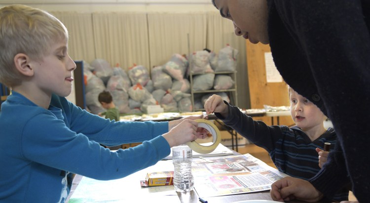 Food Corps member Socrates Alicea works with Luke Oyston, 5, right, and his brother, Jayden, 8, at the Augusta Community Warming Center on the Day of Service for Martin Luther King Jr. on Monday.