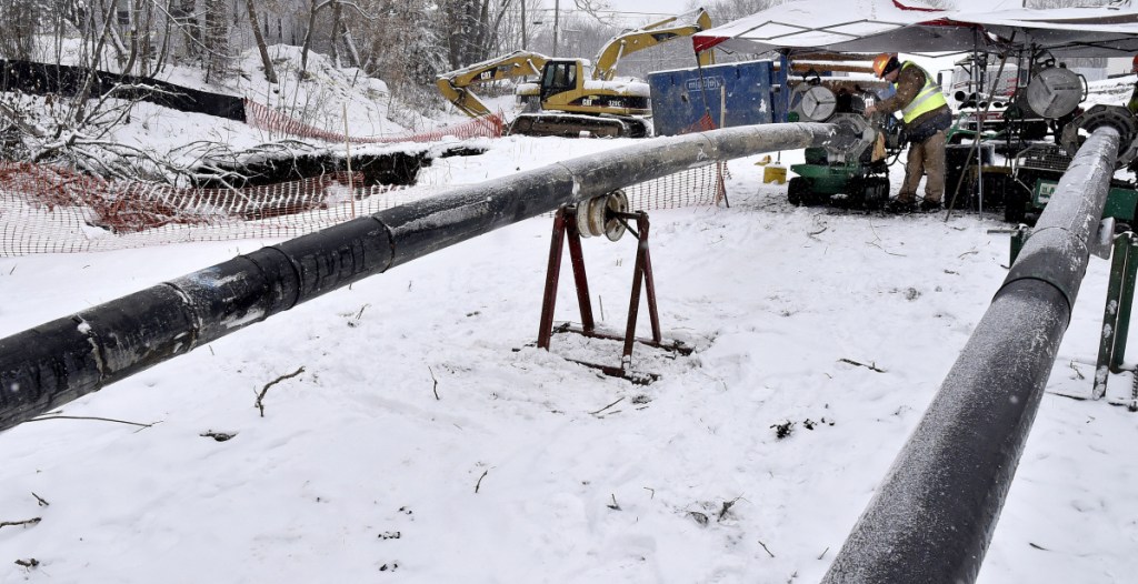 Workers with the Ted Berry Co., of Livermore, join sections of pipe to create a bypass for a 24-inch sewer line Wednesday after a large sinkhole exposed sewer and drain pipes off Halifax Street in Winslow.