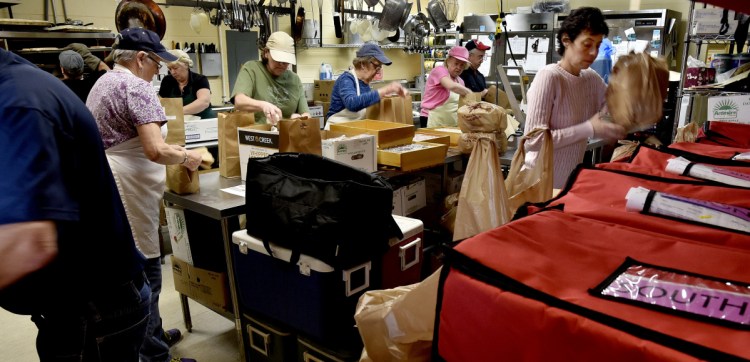 Angela Derosby, right, places meals in color-coded containers for the Meals on Wheels program Thursday that were assembled by busy volunteers in the kitchen at the Muskie Center in Waterville.