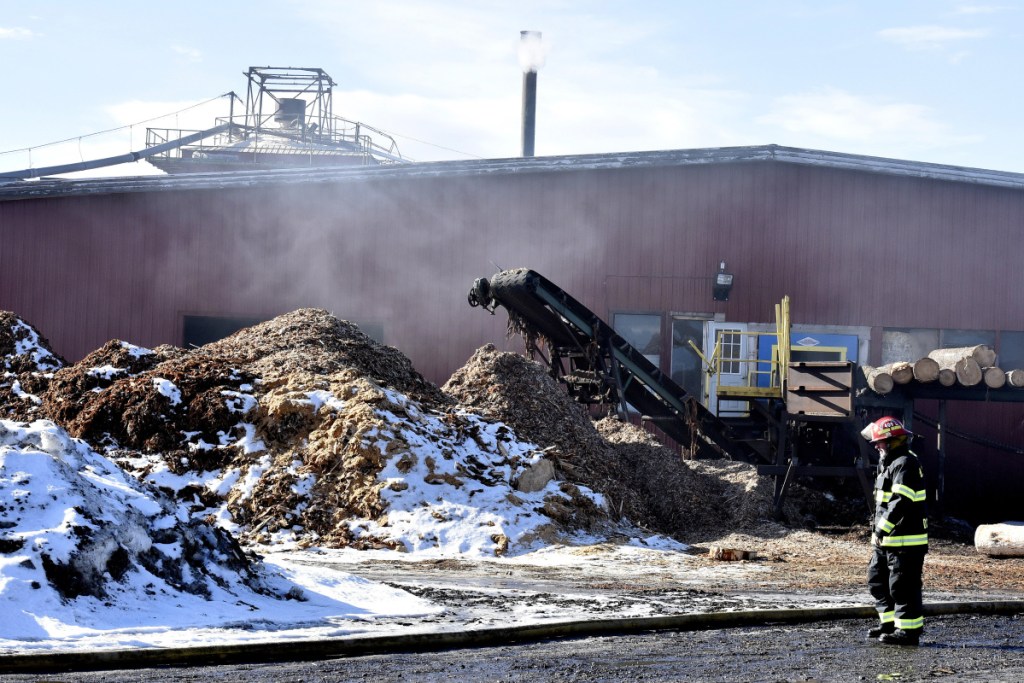 A firefighter observes smoke coming from one end of the sawmill building at the Hancock Lumber company while assisting other firefighters who were putting out a fire at the mill in Pittsfield on Sunday.