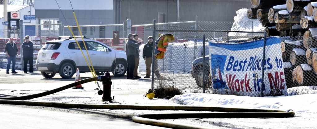 Employees at  the Hancock Lumber company in Pittsfield watch as firefighters extinguish fire at the mill on Sunday.