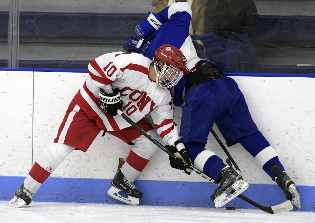 Cony's Michael Boivin, left, reaches for the puck under Lisbon/Mt. Ararat/Morse's Noah Magda during a Class A North game Tuesday in Hallowell.