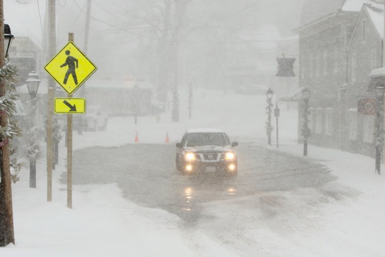 A driver navigates a flooded road at Dock Square in Kennebunkport just after high tide during Thursday’s storm.
