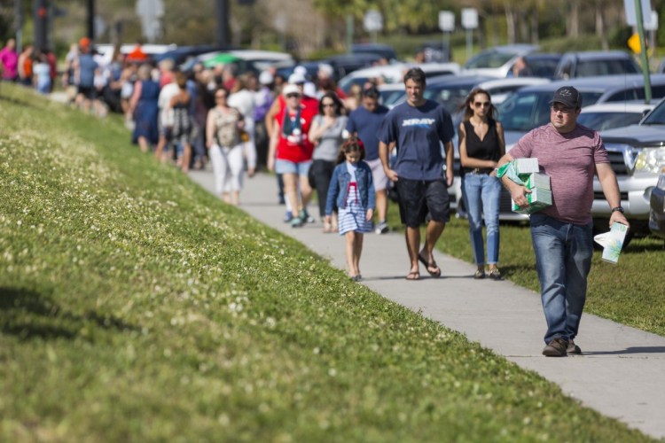 Chris McCormick, far right, from First Priority of South Florida, carries boxes of tissues for grieving community members outside of Marjory Stoneman Douglas High School in Parkland, Fla., on Sunday.