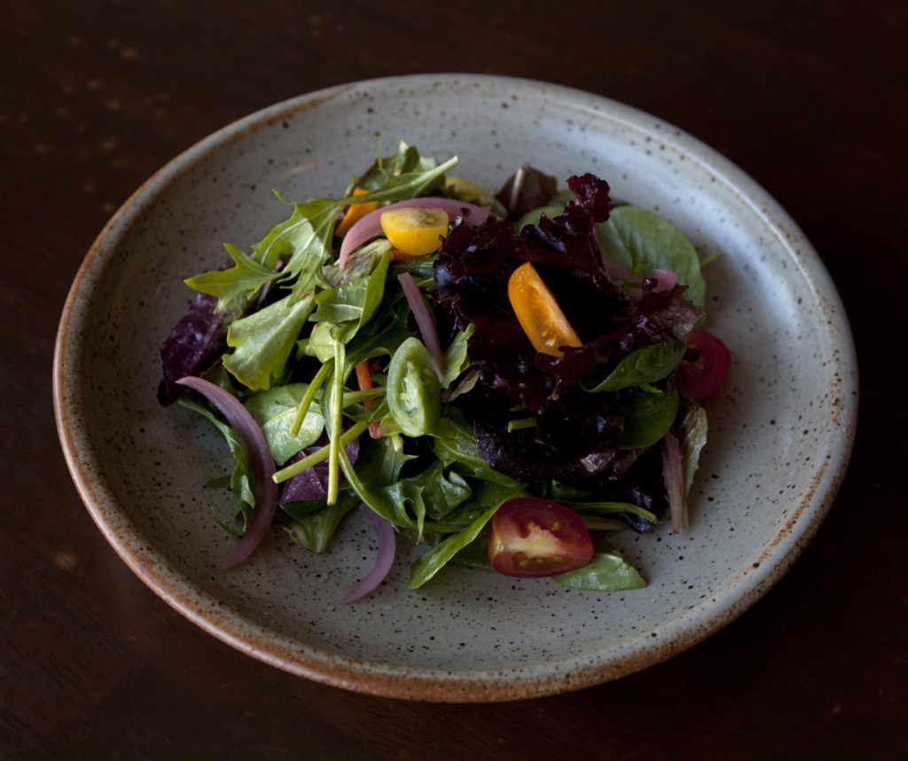 The house salad, with greens, carrots, peppers, pickled red onions and cherry tomatoes.