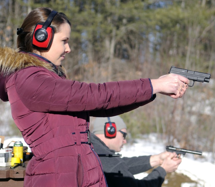 Katherine Pollock fires a pistol with Rob Sibley on Jan. 6, 2016, at the Department of Inland Fisheries & Wildlife range in Augusta.