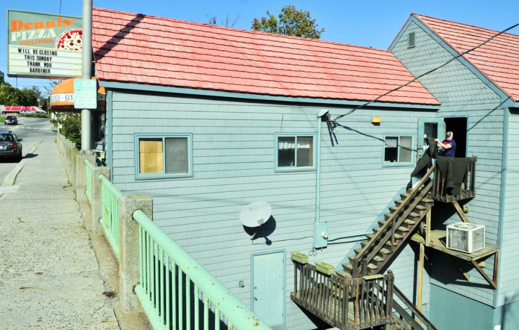 Andrew Waller shakes out rugs Sept. 23, 2017, at Dennis' Pizza in Gardiner. The recently closed restaurant was bought by Maine Department of Transportation and will be demolished Monday to make way for new bridge construction.