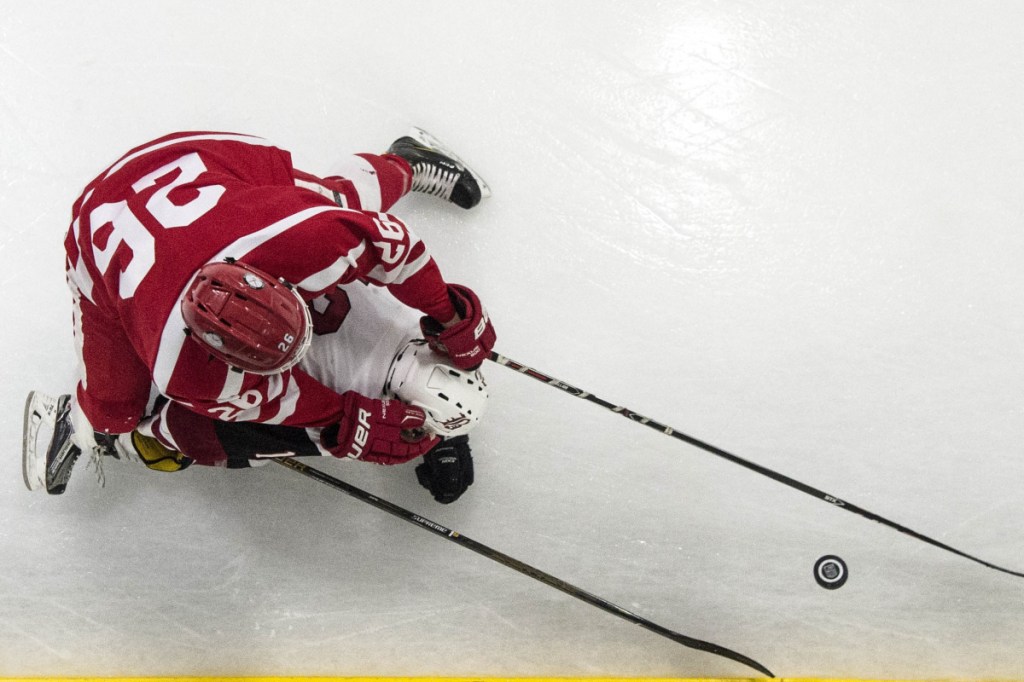 Bangor's Josh Sherwood (12) tries to maintain control of the puck as he falls to the ice while Cony's Joseph Arps (26) tries for the steal Tuesday in Bangor.