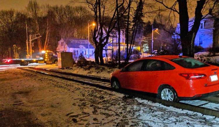 A tow truck arrives to remove a car stuck on the tracks in Portland's Woodfords neighborhood.