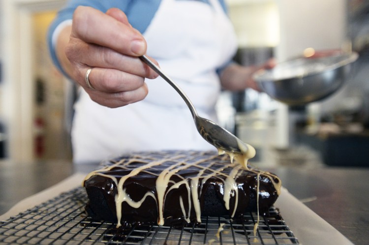 Stacy Cooper spoons an Irish Cream Drizzle made with confectioners' sugar and Irish cream liqueur on brownies at Biscuits and Company in Biddeford. Cooper uses beer in her brownies – she prefers her hometown of Biddeford's Banded Horn Stout.