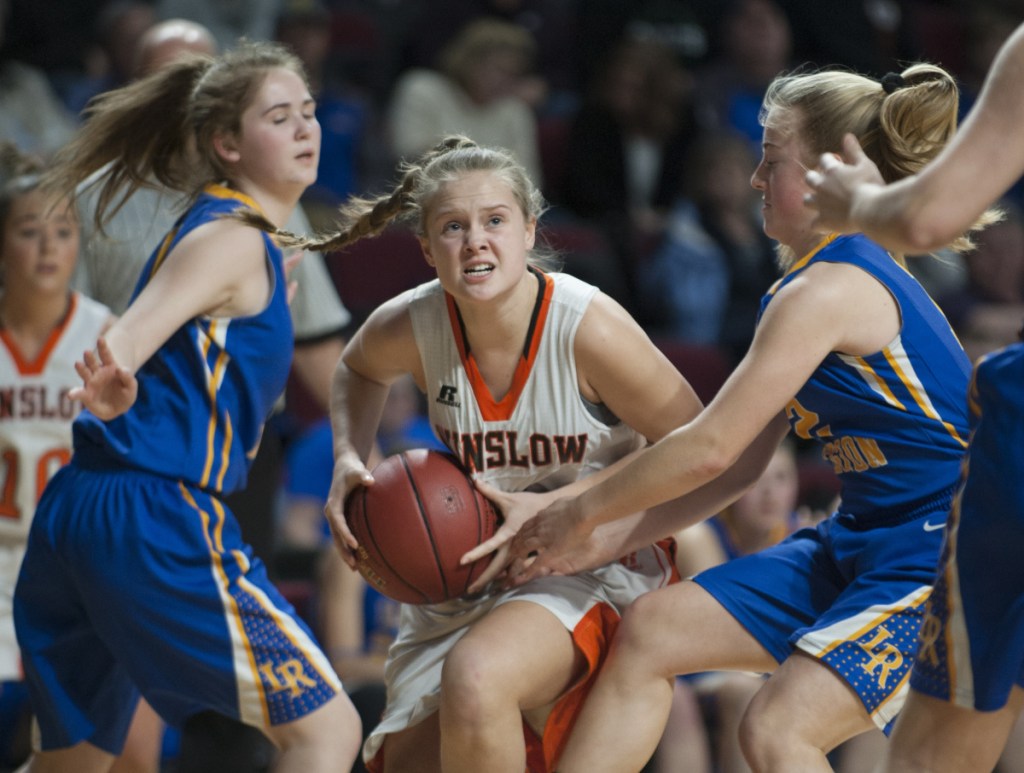 Winslow's Silver Clukey splits Lake Region defenders Rachel Shanks, left and Shauna Hancock on her way to the basket during the Class B state championship game Friday night at the Cross Insurance Center in Bangor.