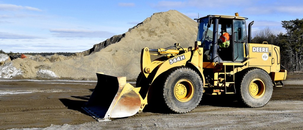 Moe Labbe, of the Winslow Public Works Department, smooths ruts Tuesday near the town sand pile after loading trucks for a snowstorm that is forecast to begin late Wednesday and last through Thursday.