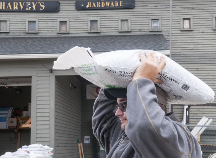 Liam Crocker, of Randolph, carries a bag of wood pellets on his head to a friend's car on Tuesday at Harvey Hardware in Gardiner, ahead of a snowstorm forecast for Wednesday night into Thursday.