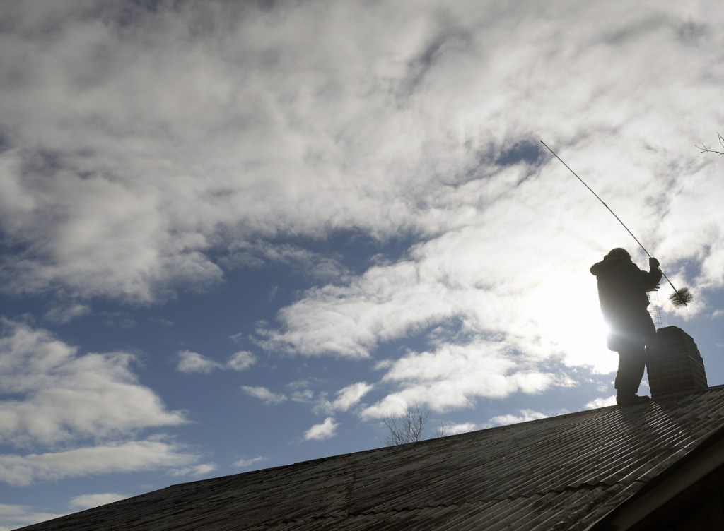 Marion Messenger sweeps the chimney on her home Tuesday in Wayne. Messenger said she likes to give the primary source of heat a brush every three weeks to keep slow-burning fires from creating much creosote. She climbed up there to get ahead of the snowstorm in the forecast for Wednesday night into Thursday.