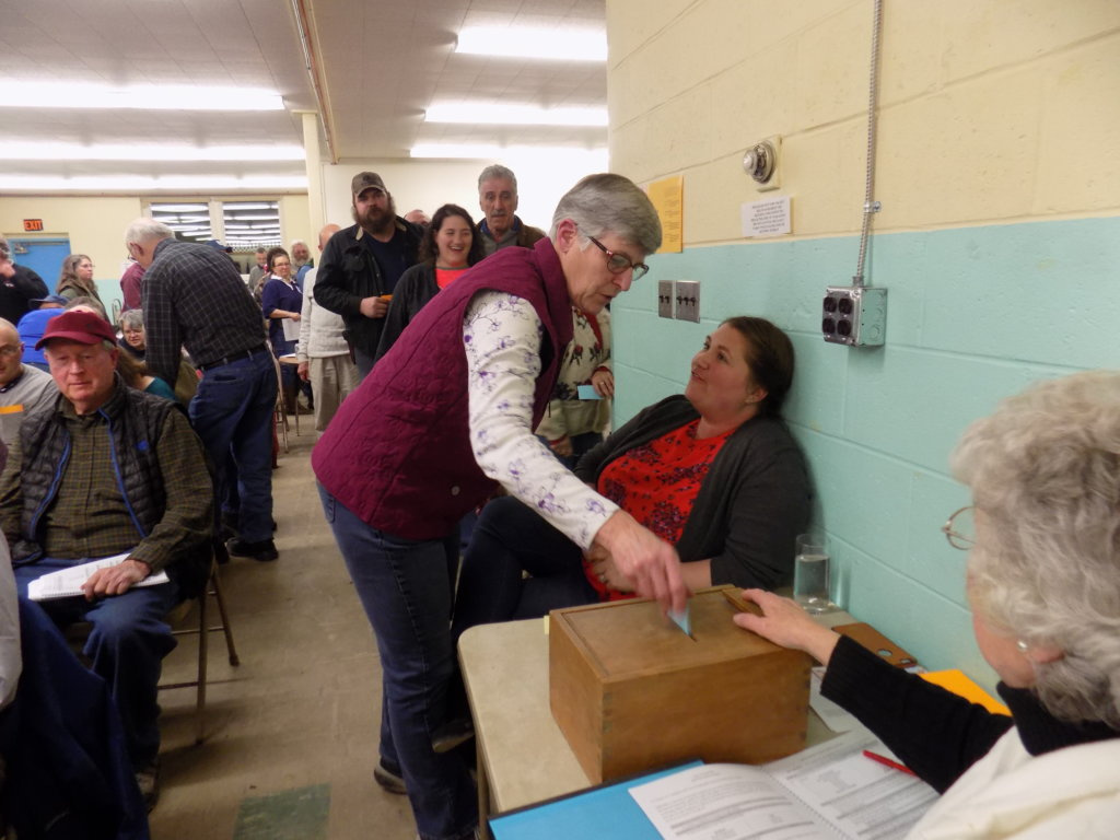 Anne Lambert casts her ballot Monday night at the Chesterville Town Meeting as Glenda Barker oversees the ballot box.