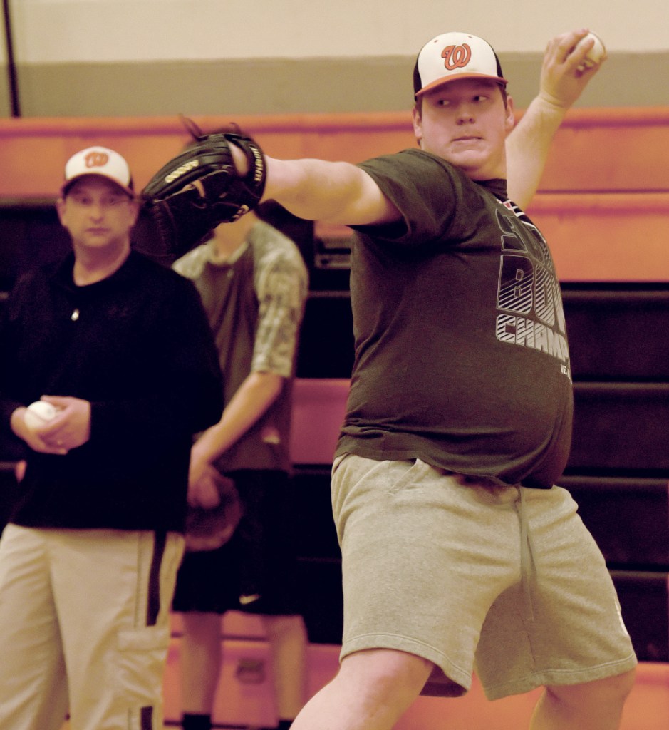 Winslow pitcher Cameron Winslow throws during practice for pitchers and catchers Monday afternoon. Assistant coach Kris Targett, left, observes.
