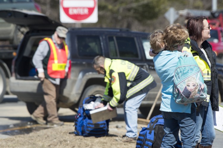 A woman holds her child while waiting for her Jeep be loaded onto a wrecker Wednesday at the intersection of Route 3 and Lakeview Drive in China. Minor injuries were reported and occupants of both vehicles were taken by ambulance to the hospital for precautionary reasons.