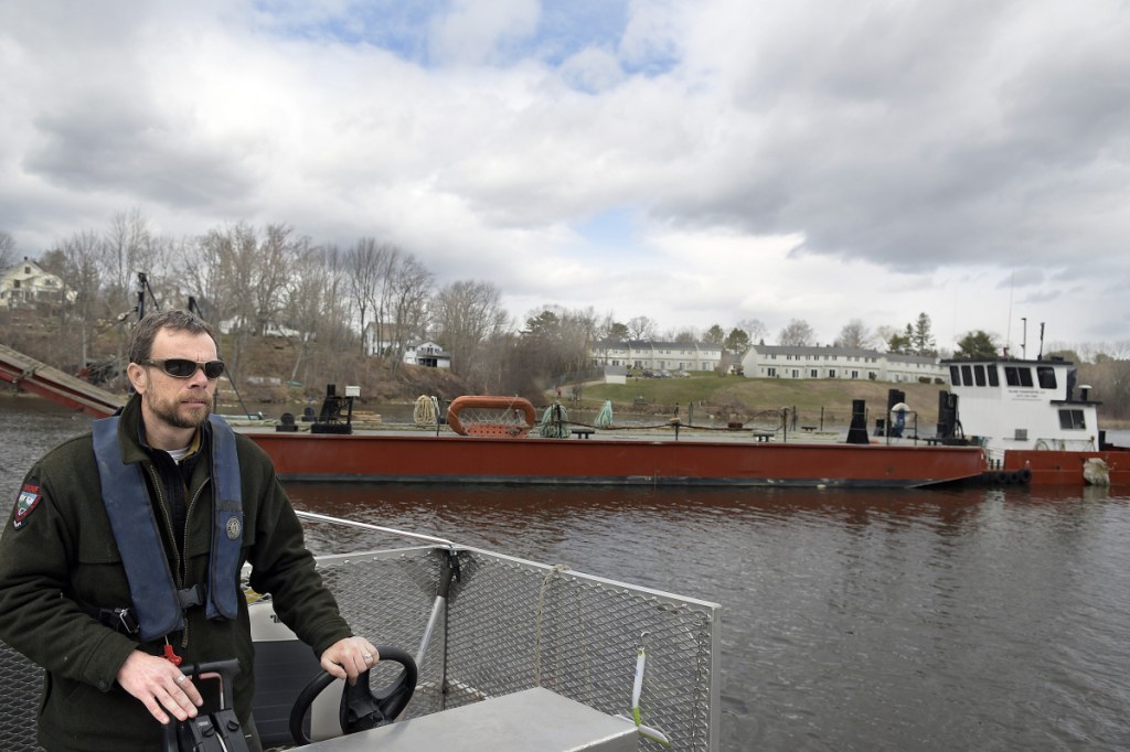 Department of Inland Fisheries & Wildlife biologist John Pratte crosses the Kennebec River on Wednesday to Swan Island, in the Kennebec River near in Richmond. More than 100 acres of trees were blown over on the island during a windstorm in 2017 that has compelled the agency that oversees the wildlife refuge to initiate a salvage operation to remove the down trees. The barge anchored in the river, at right, hauls logging machinery between the mainland and island.