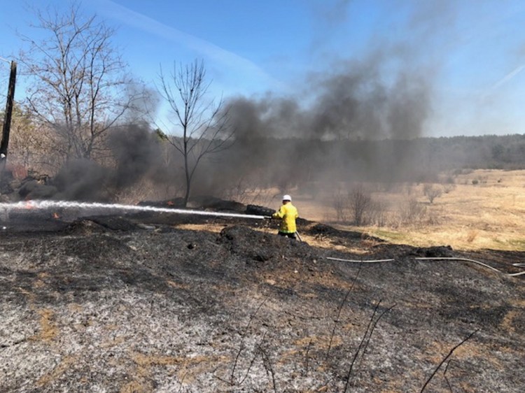 Fairfield Fire Chief Duane Bickford trains a fire hose on a pile of tires Monday outside the former Fox Den dance hall on Middle Road in Skowhegan at the Fairfield town line.