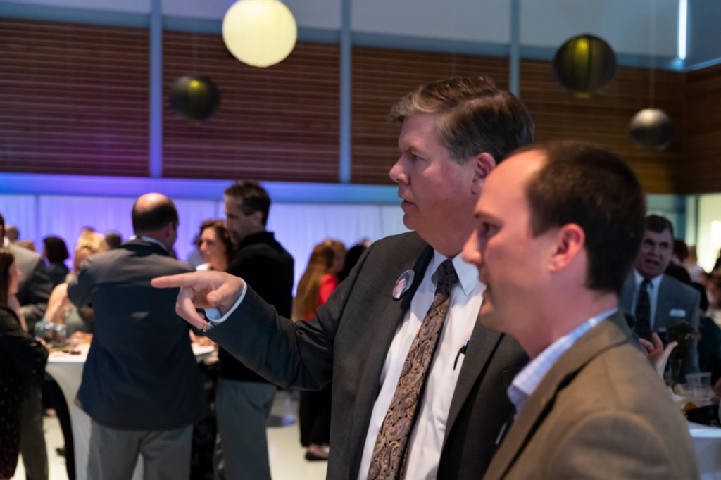 Chuck Hays, CEO of MaineGeneral Medical Center, points across the room Thursday while in conversation with Nate Cotnoir, senior vice president of commercial banking at Camden National Bank, at the Mid-Maine Chamber of Commerce Awards Ceremony at Kennebec Valley Community College in Fairfield.