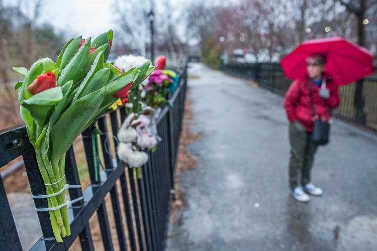 Linda Scott stands on the pedestrian bridge and looks at the tribute she organized Wednesday for two young brothers who fell into the Androscoggin River on Tuesday night. 
