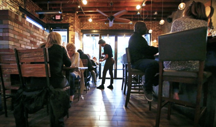 Boda host Eric Schnare, center, pours water for newly seated guests. Boda is among many busy Portland restaurants that do not take reservations.