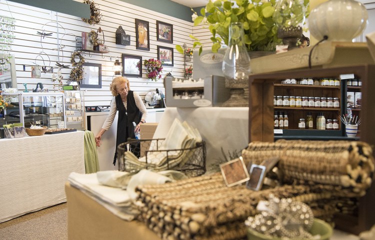 Carla Dumont sets up merchandise at the new location of Maine Made and More at The Concourse in downtown Waterville on Friday.