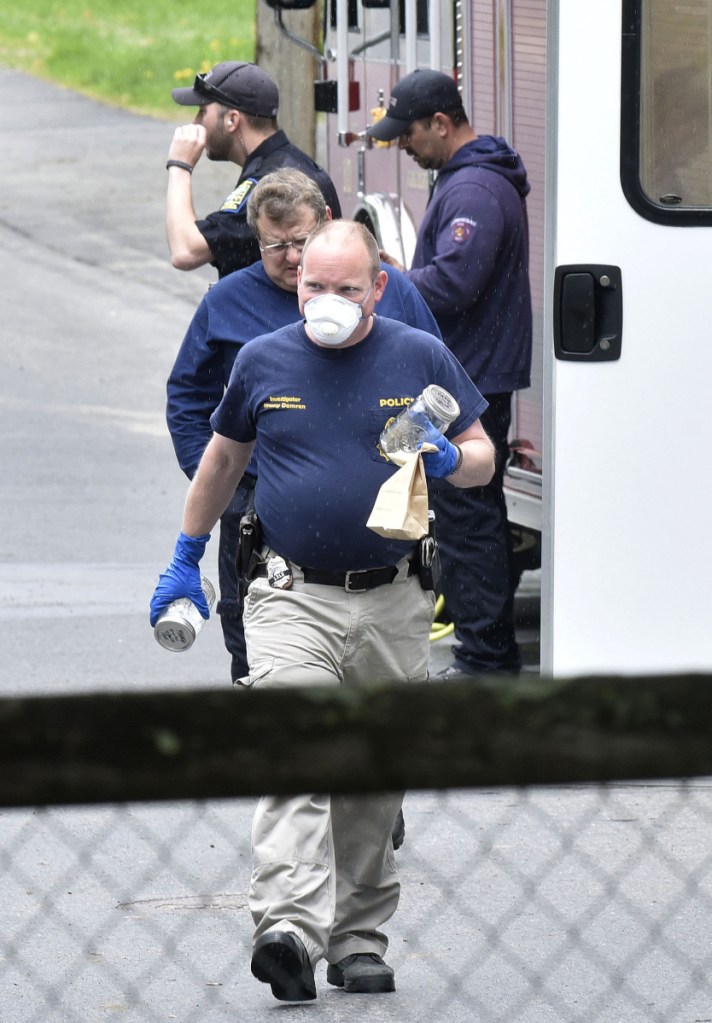 Investigator Jeremy Damren, of the Office of State Fire Marshal, carries containers of evidence taken Sunday from 15 Summer St. in Skowhegan. Investigators with that agency, state and Skowhegan police and firefighters blocked access to the home after resident Philip Ewing notified police Saturday evening that he was disabling a black powder cannon. Police observed containers of bleach, gunpowder, gasoline and other explosive materials. Area homes were evacuated.